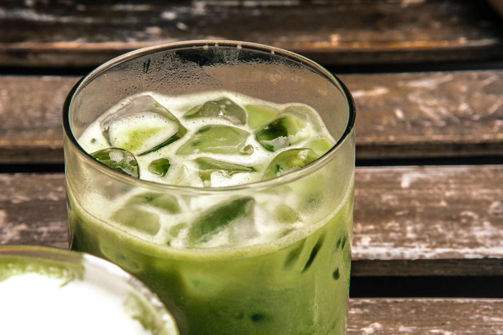 A close-up of a refreshing iced matcha latte on a rustic wooden table, highlighting its natural green color and fresh appeal.